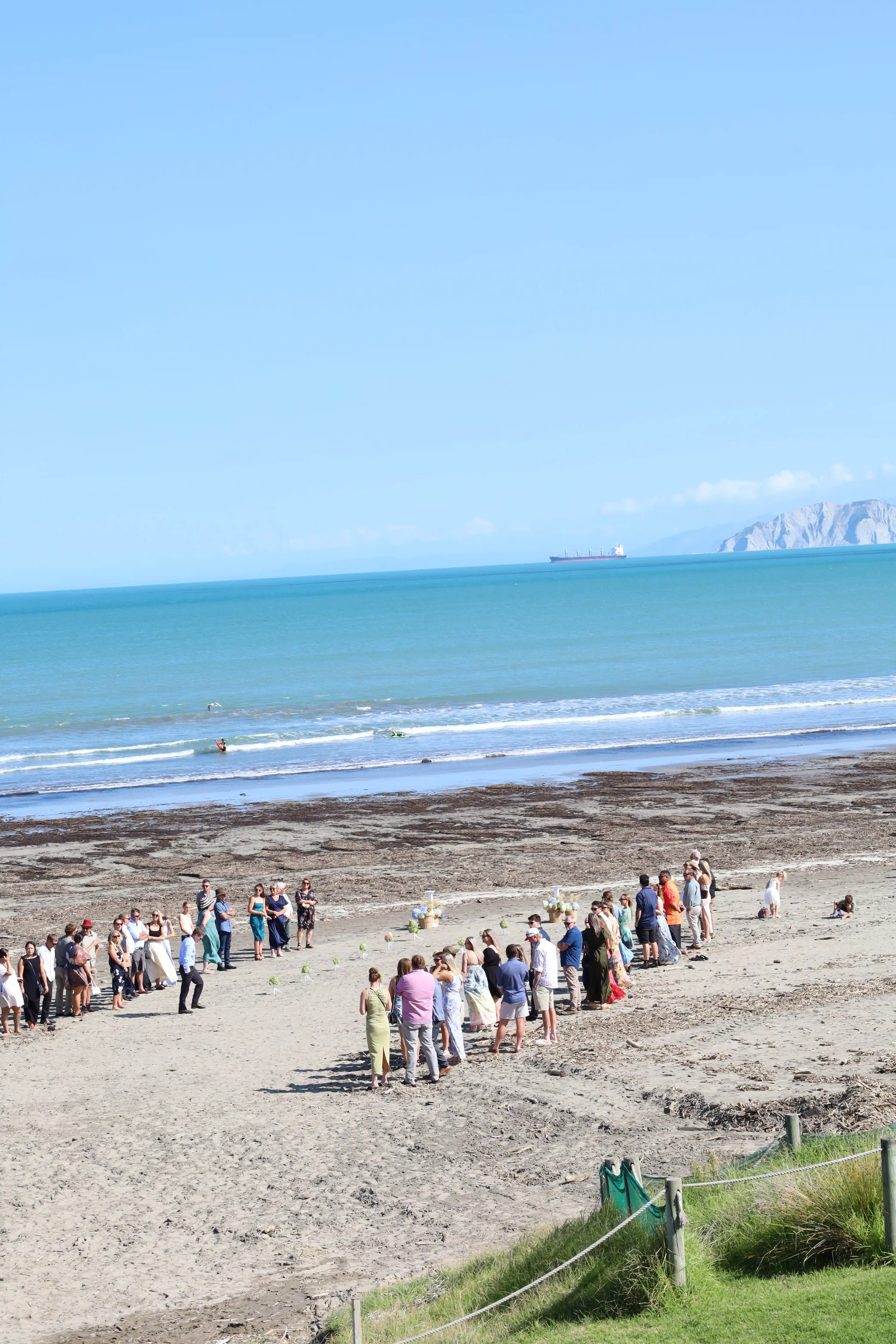 Wide angle beach wedding ceremony with Poverty Bay headland in background