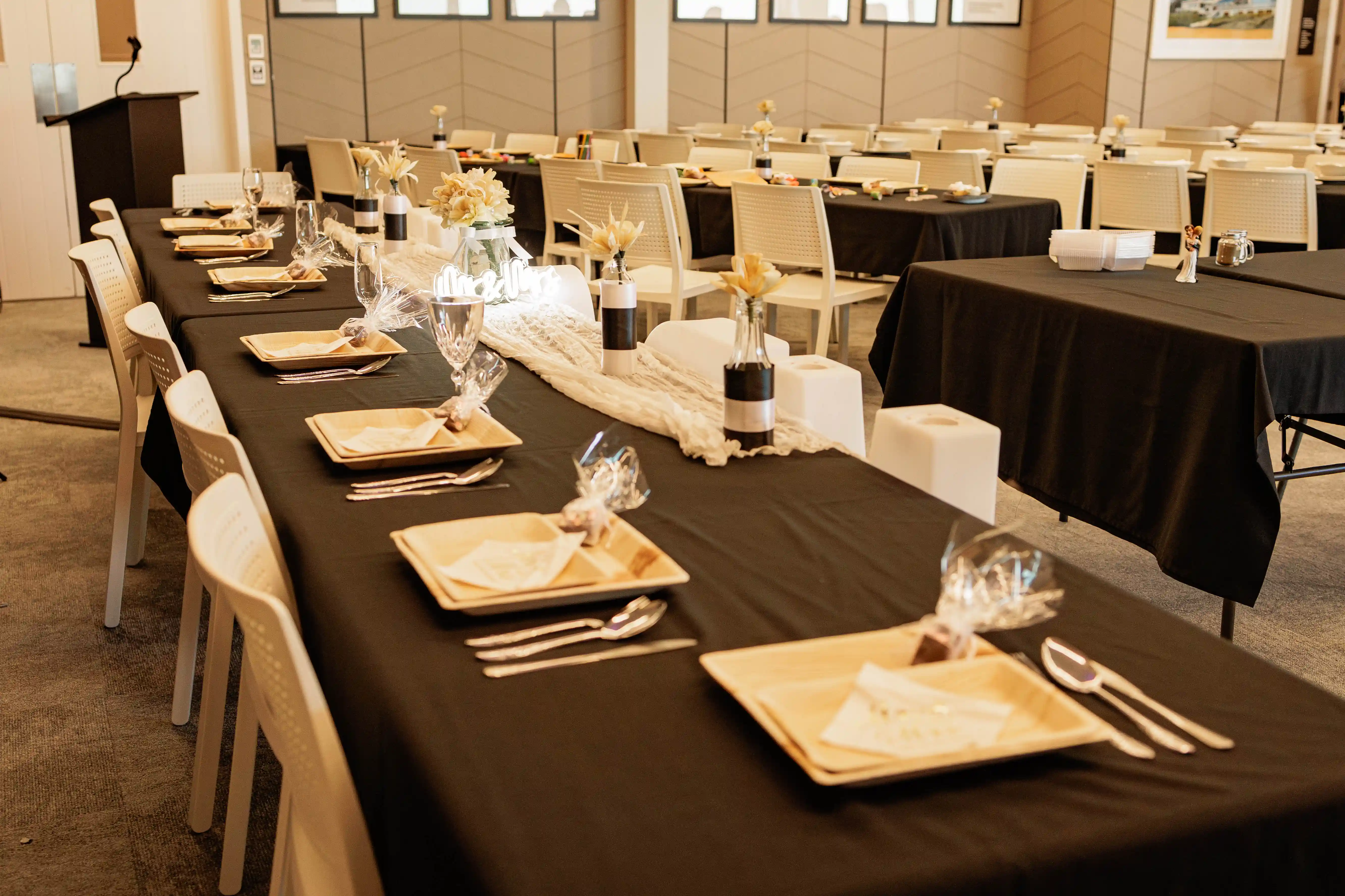 Indoor wedding reception at Gisborne beachfront venue with black tablecloths and gold charger plates