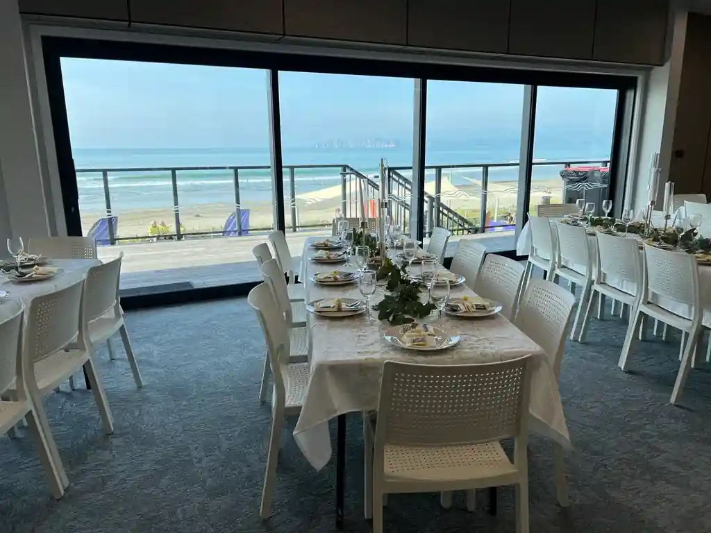 Wedding reception tables with direct beach and ocean view through floor-to-ceiling windows at Gisborne beachfront venue