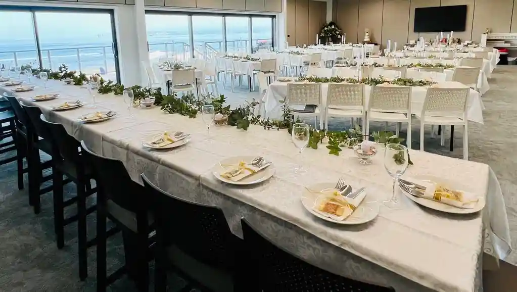 Floor-to-ceiling ocean view windows at Gisborne beachfront wedding venue with bridal and round guest tables