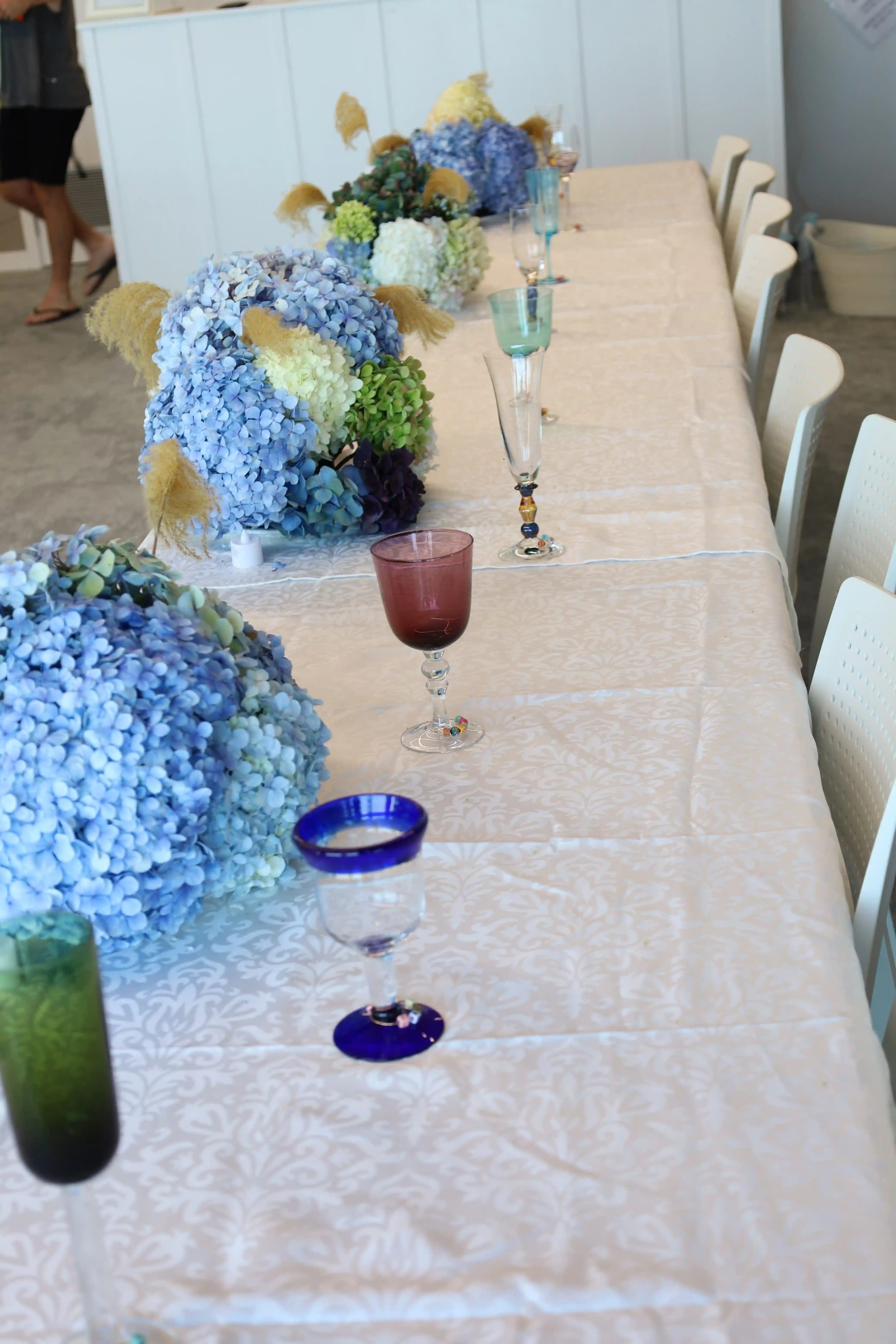 Long wedding reception table with blue hydrangea centrepieces at Gisborne venue