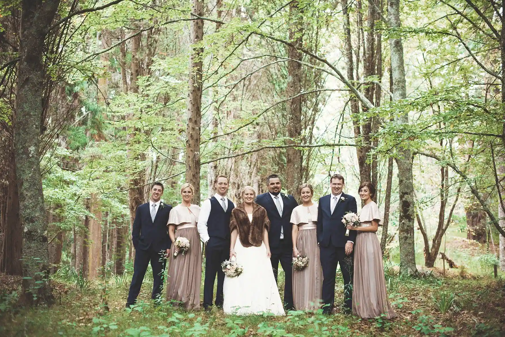 Wedding bridal party group photo in lush forest at Gisborne arboretum wedding venue