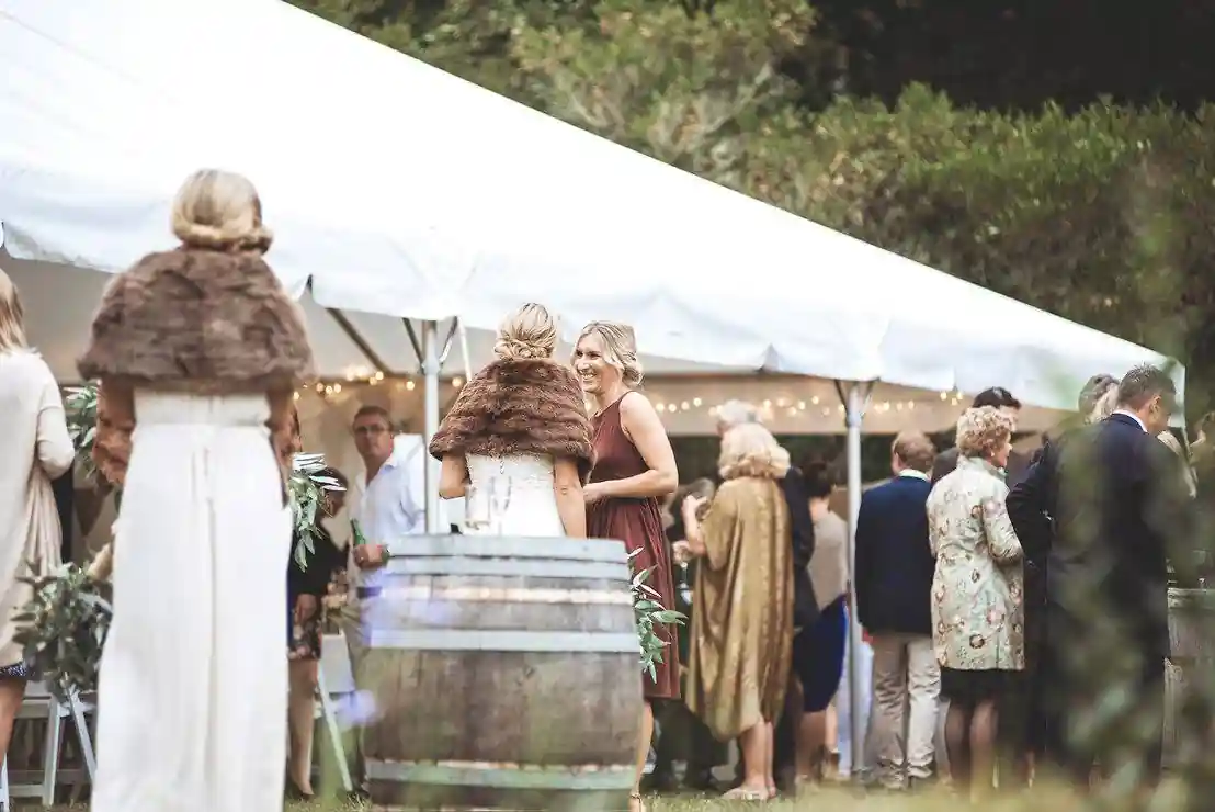 Wedding cocktail hour under marquee tent with wine barrels at Gisborne arboretum venue