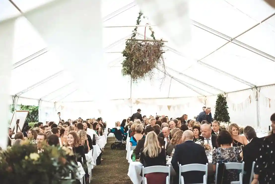 Full wedding reception in marquee with hanging greenery