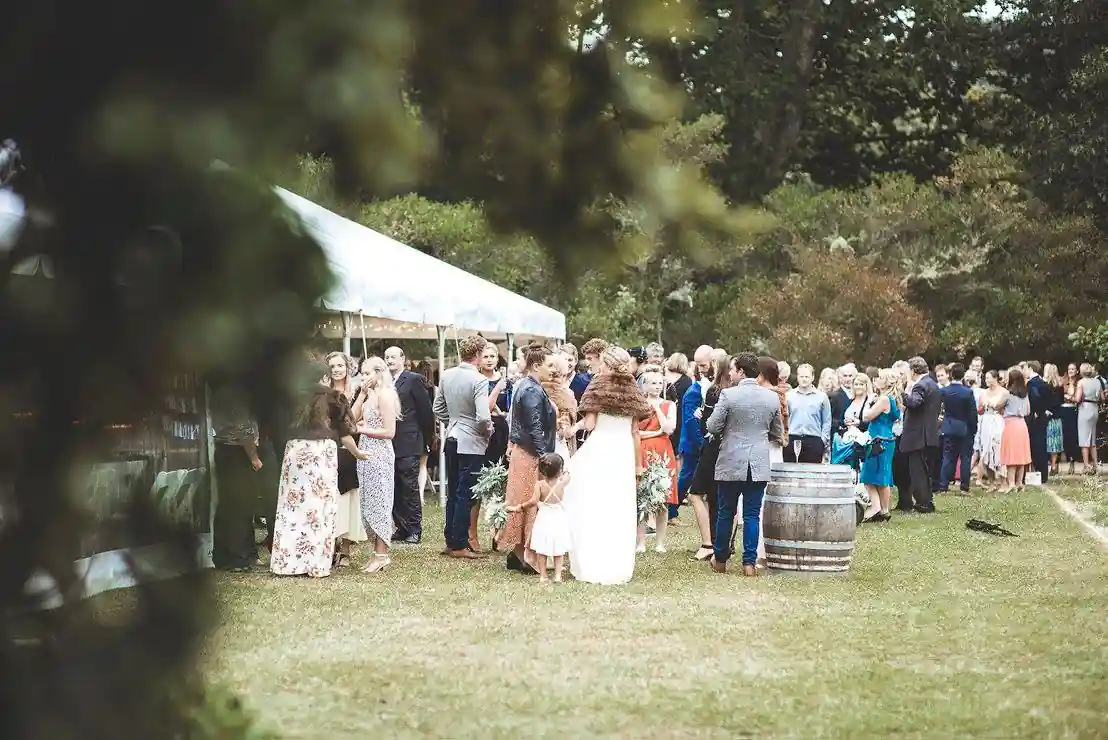 Outdoor cocktail hour crowd with wine barrels at arboretum wedding